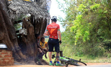 A cycling rider chatting with small children in Sri Lankan village