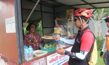 cycle rider buying foods from a lady